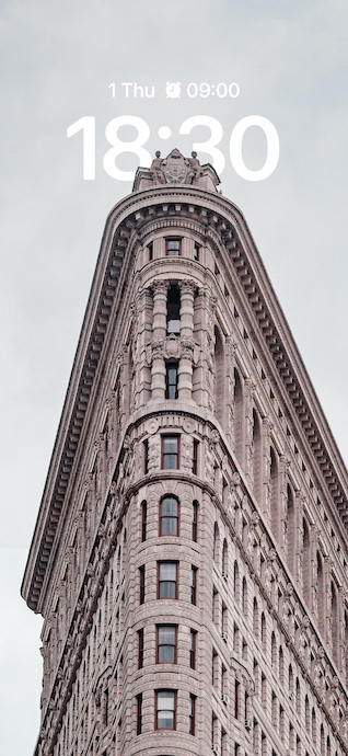 從低角度拍攝的紐約熨斗大廈，背景為陰天，展現了細緻的石材建築細節與獨特的契形形狀。