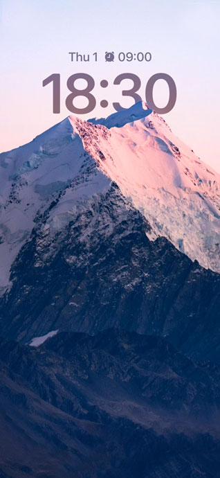 被夕陽染成粉紅色的險峻雪山頂峰，山腰處呈現深藍色的陰影。