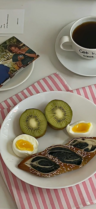 白いお皿に乗ったキウイ、卵、パンとコーヒーの入ったカップの俯瞰写真。